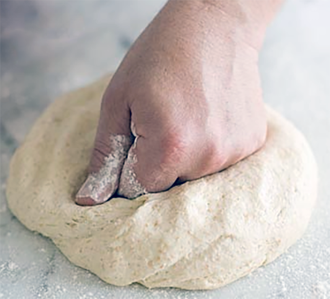 Knocking dough back by punching it