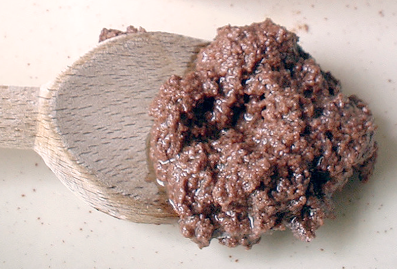 Olive tapenade presented on a wooden spoon