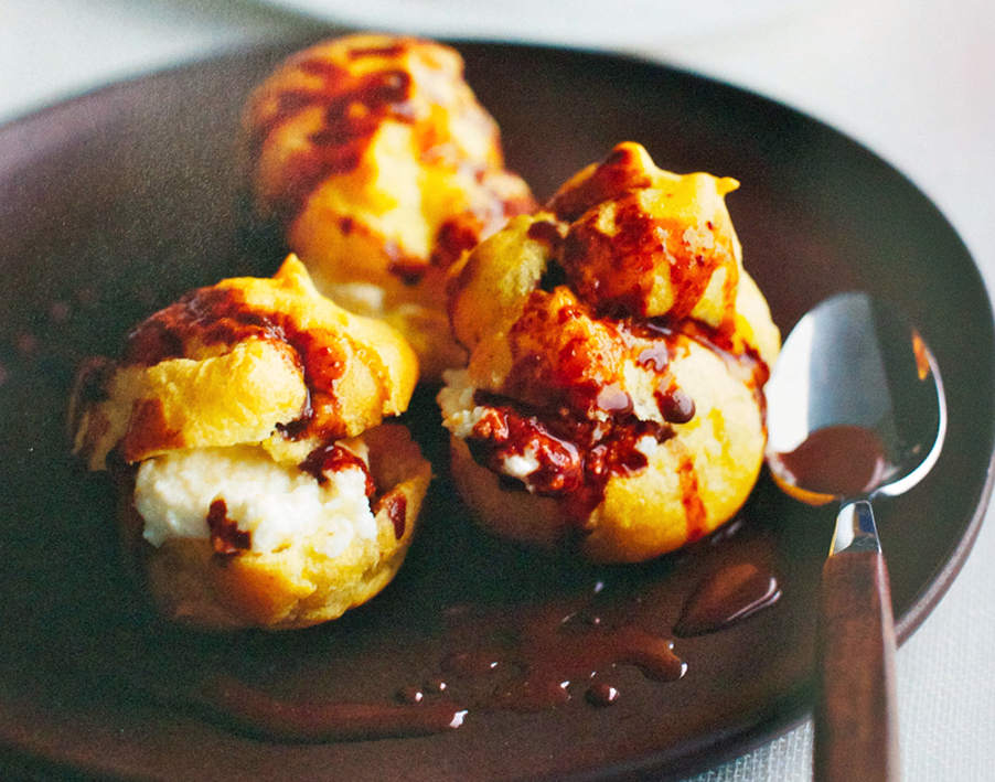 Orange profiteroles on a plate served with chocolate-orange sauce