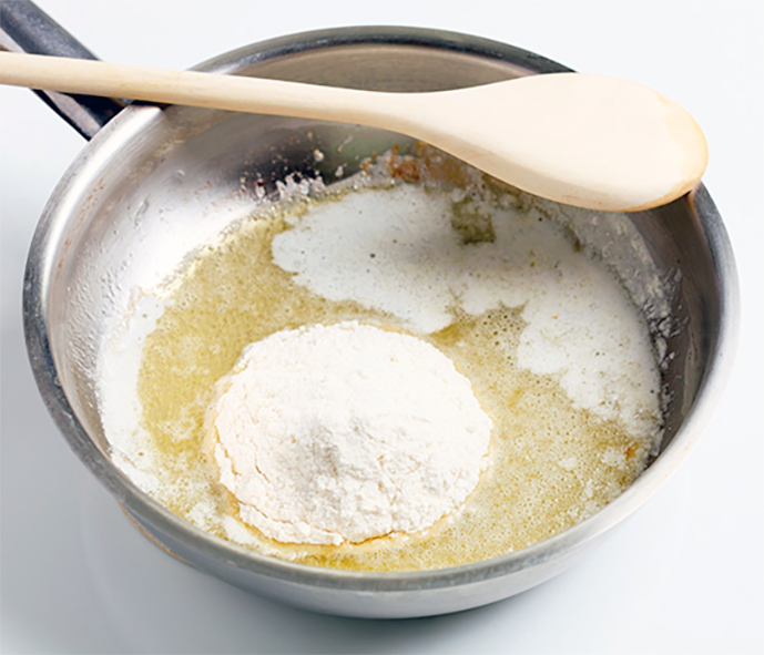Preparing a roux by blending flour with melted butter