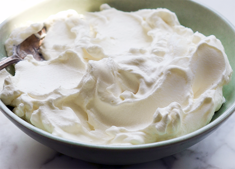 Thick whipping cream in a wooden bowl