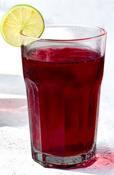 agua de jamaica in a tall glass garnished with a slice of lime