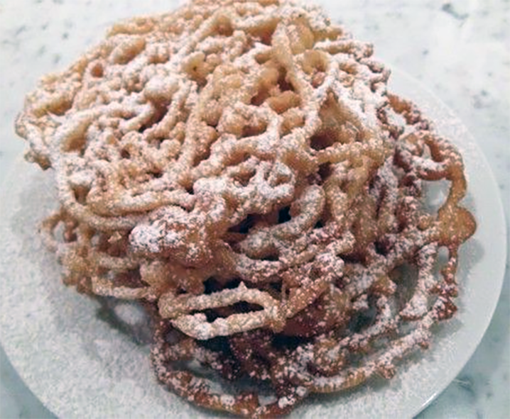 three funnel cakes stacked on a plate dusted with powdered sugar