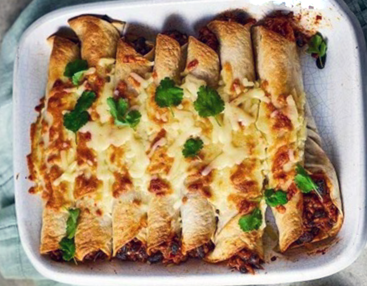Beef enchiladas topped with cheese in a white baking dish