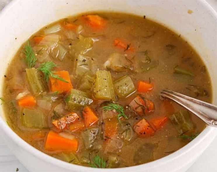 soup of potatoes, turnips, carrots, onions, mushrooms and celery in a white soup bowl