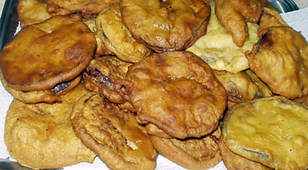 battered and fried aubergine slices on a tray lined with kitchen paper