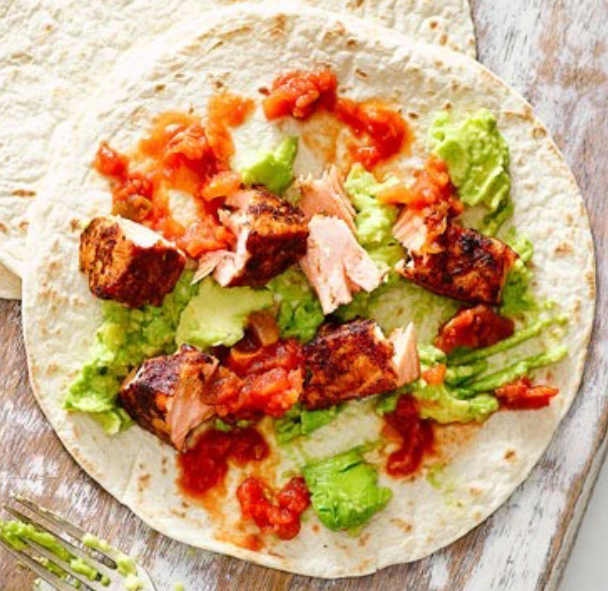 Tortilla topped with mashed avocado and flaked blackened salmon