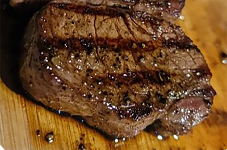 cajun marinated rib-eye steak on a wooden chopping board