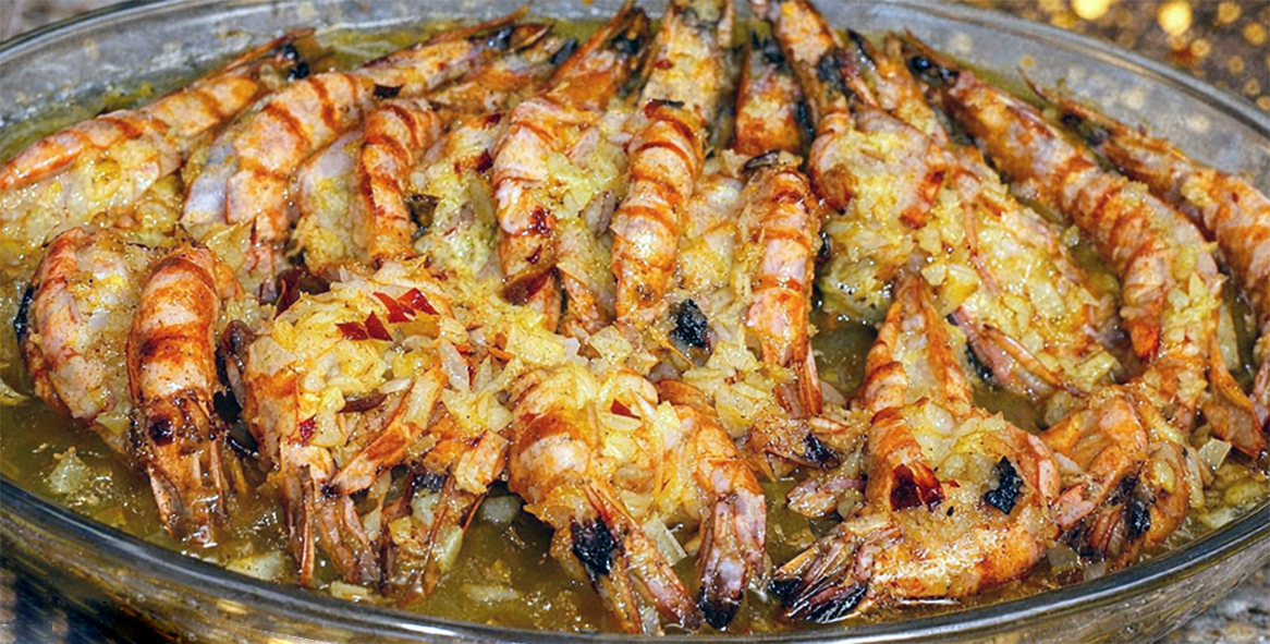 Prawns with garlic cooked in margarine arranged in an oval glass serving dish