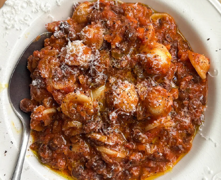 ragu of carlin peas in a mixed vegetable and tomato base served with orichette pasta in a white bowl