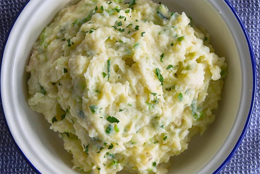 champ of mashed potato with spring onions served in an enamelled dish