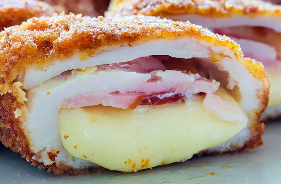 Breaded chicken cordon bleu split in half to reveal the ham and cheese filling inside