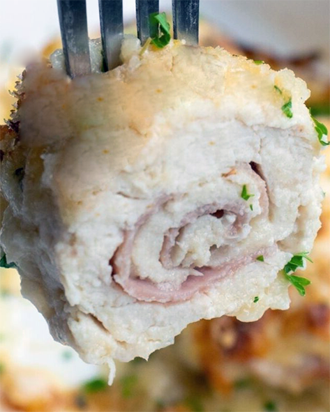 rolled chicken and ham escalope picked up with a fork