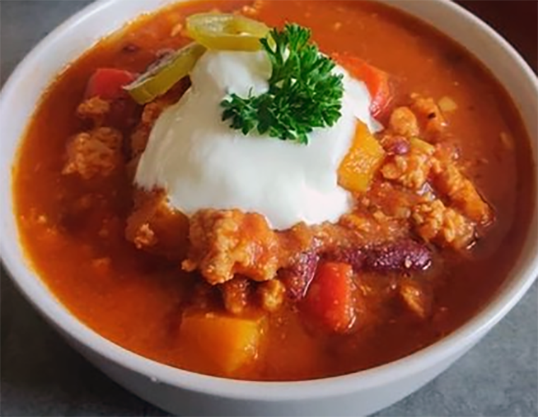 chili chicken stew served in a bowl garnished with sour cream