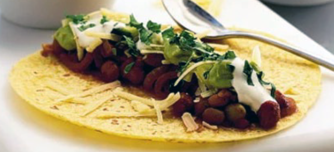 tortilla topped with cheese, chilli beans, sour cream, guacamole and coriander