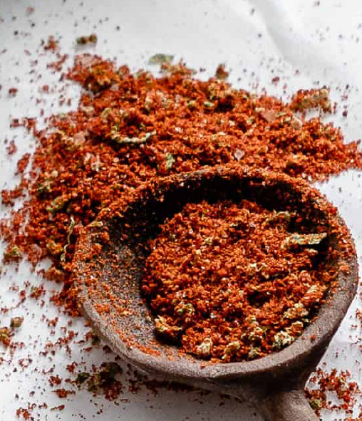 chilli lime seasoning blend spilling from a wooden spoon