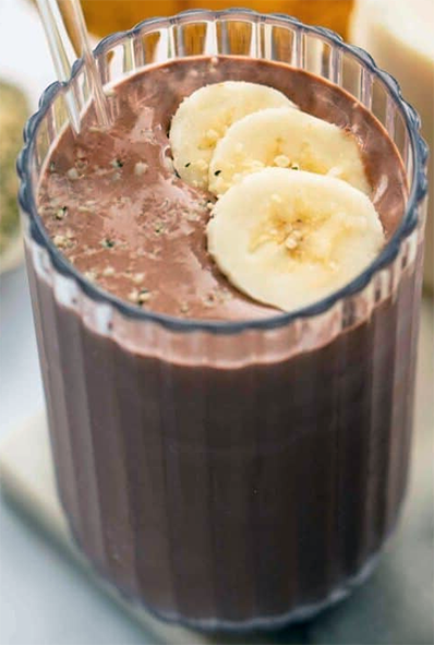 chocolate, banana and vanilla frozen yoghurt smoothie in a glass garnished with sliced bananas