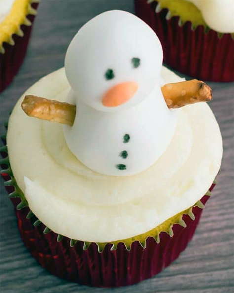 cupcake with white icing topped with a white fondant snowman