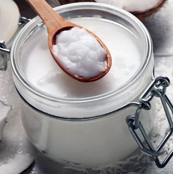 thick coconut cream in a glass jar with a wooden spoon