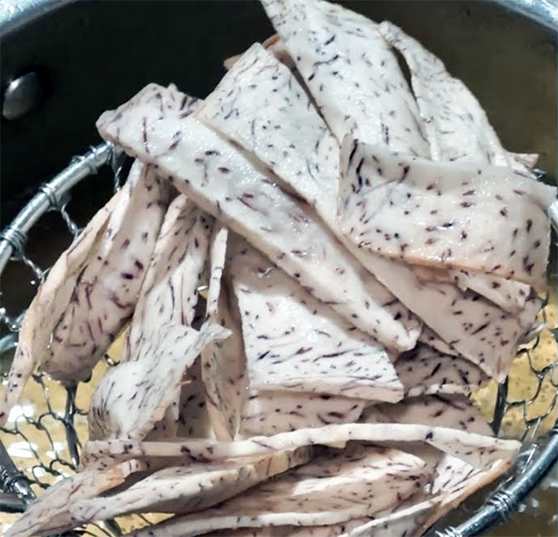 cocoyam (taro) chips being lowered into a deep fat fryer