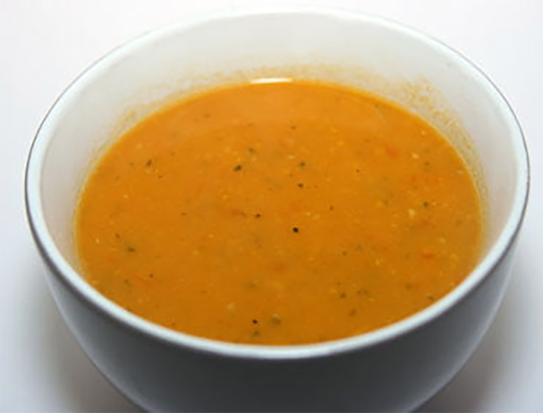 courgette soup with tomatoes served in a blue bowl