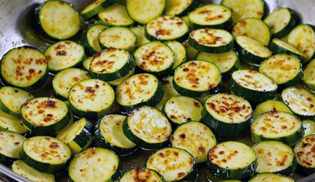 boiled courgette slices being fried in a pan with butter