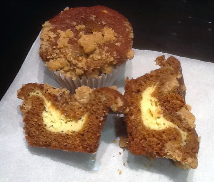 two gingerbread muffins with one split open to reveal the cream cheese filling