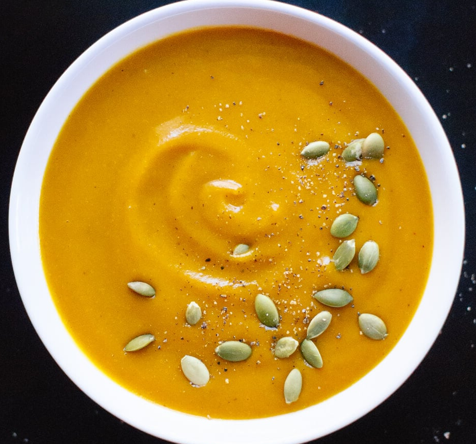 cream of pumpkin soup garnished with pumpkin seeds in a soup bowl