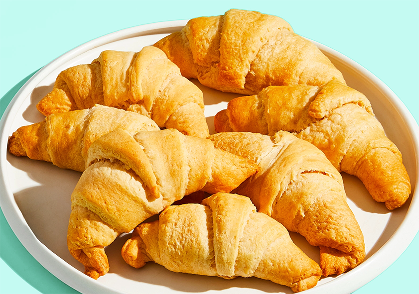 seven crescent rolls arranged on a white plate