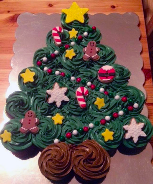 Decorated cupcakes arranged on a metal sheet in the shape of a Christmas tree