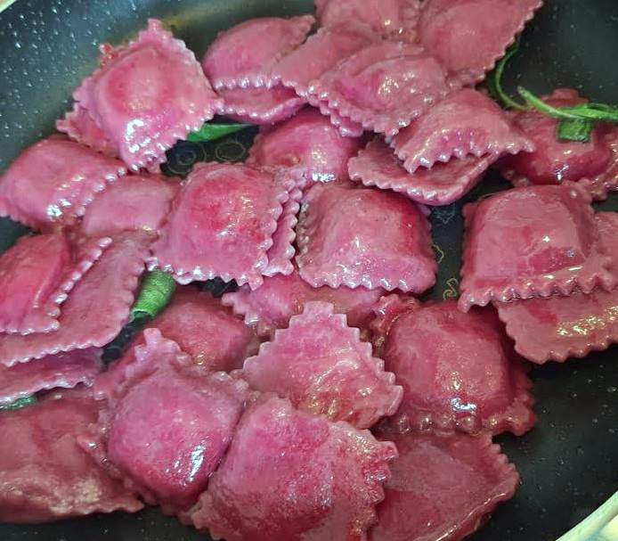 dandelion ravioli made with beetroot pasta in a frying pan