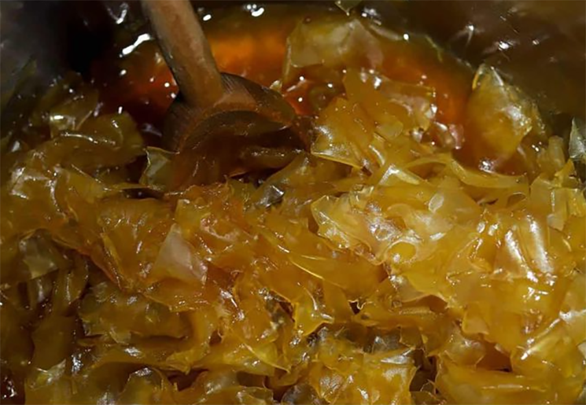 doce de papaia cooking in a saucepan with a wooden spoon