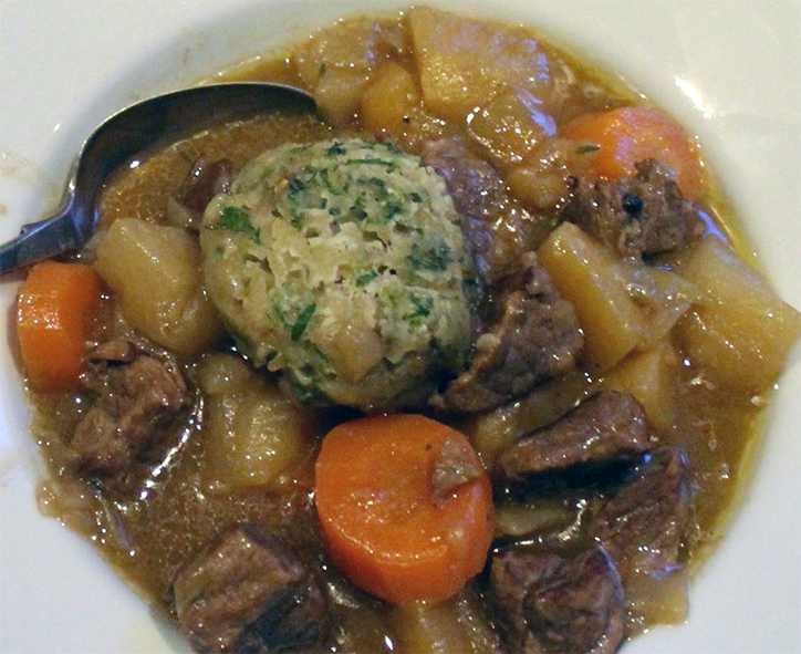 Exeter stew served in a bowl topped with a herby suet dumpling