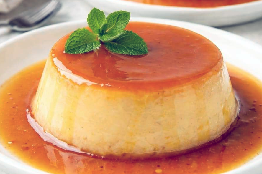 Filipino leche flan on a plate with syrup and a sprig of mint