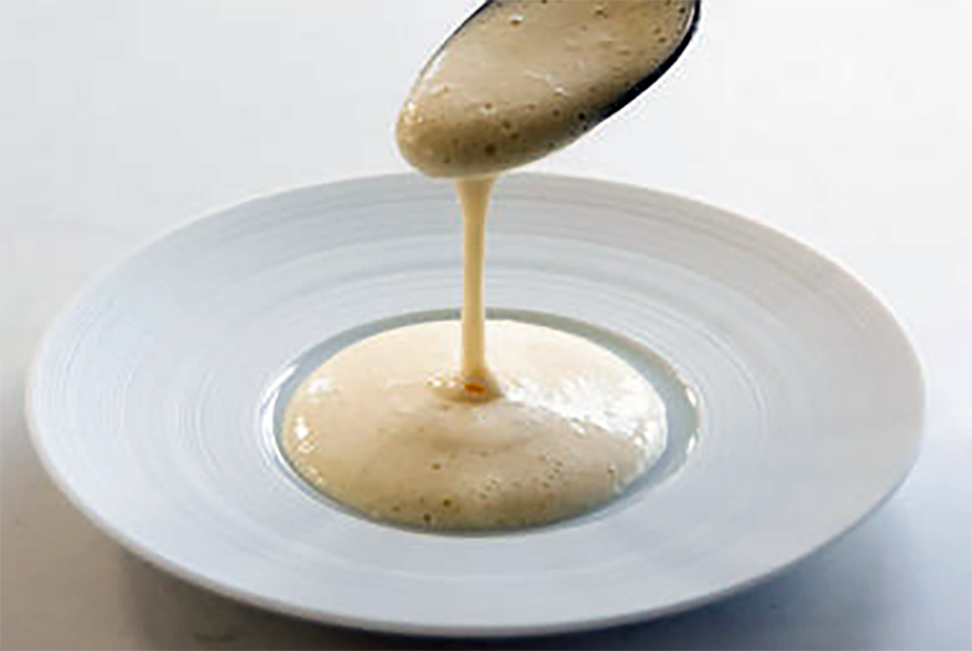 foamy sherry sauce drizzled off a spoon and onto a plate