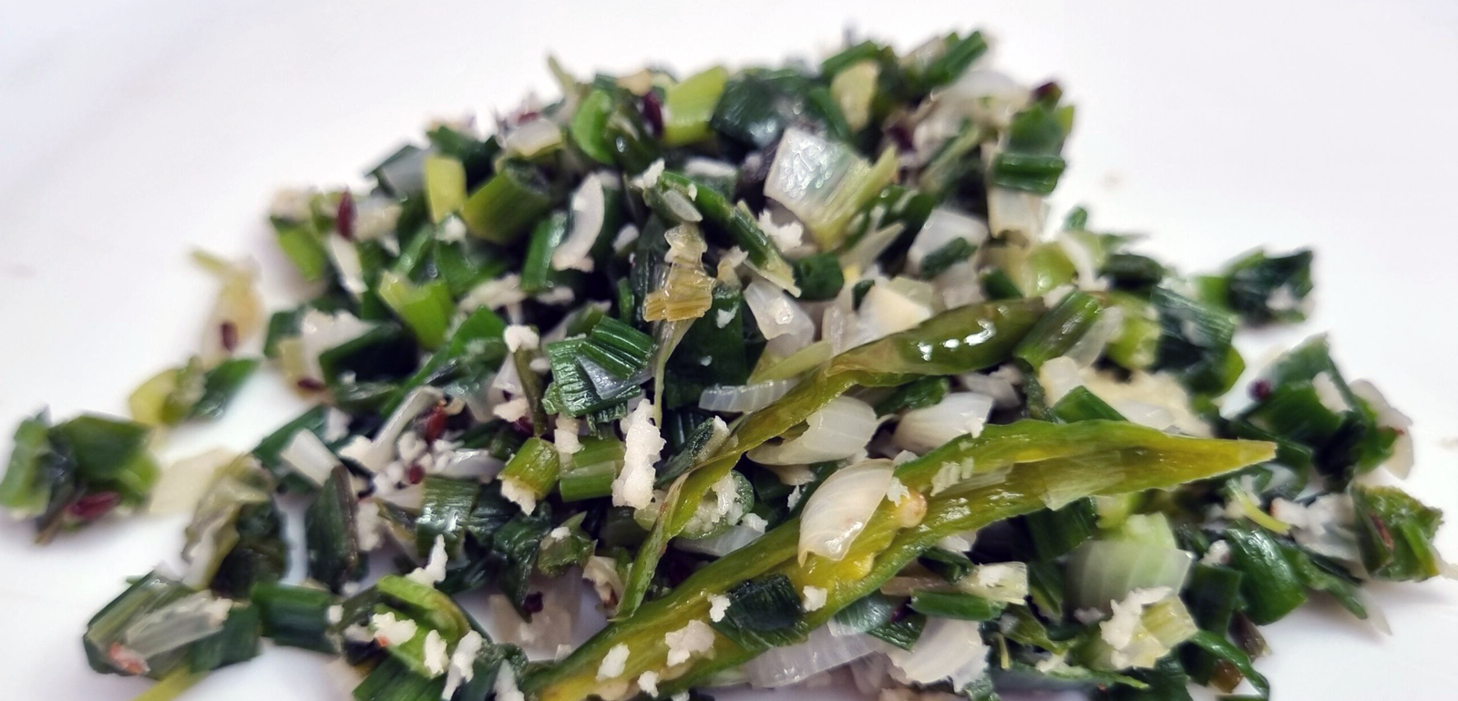 stir-fried deadnettle greens and spring onion on a white plate