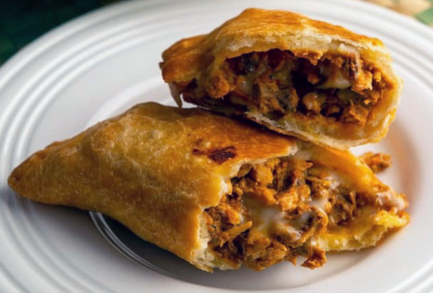 fried empanada split in half and served on a white plate