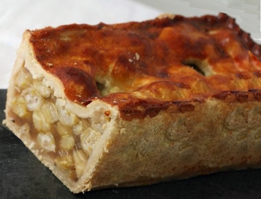 gooseberry raised pie bound with elderflower gelatine and baked in hot water crust using a loaf tin with a golden top and with the end removed to reveal the filling.