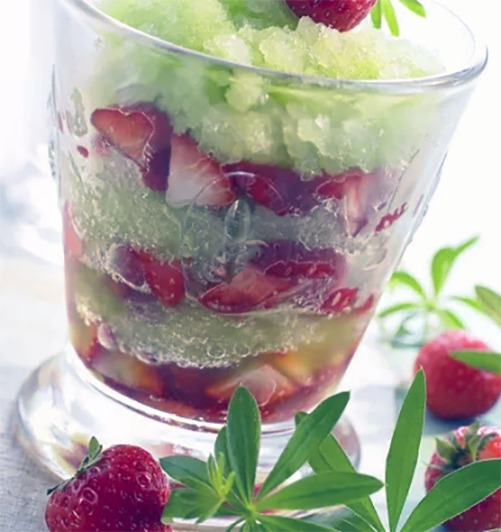 granita with woodruff layered with fresh chopped strawberries in a dessert glass
