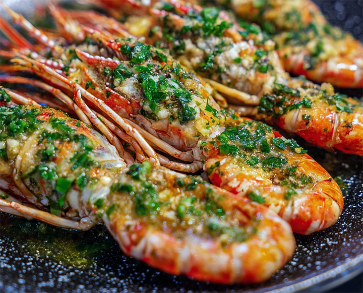 grilled langoustine topped with herb butter served on a plate