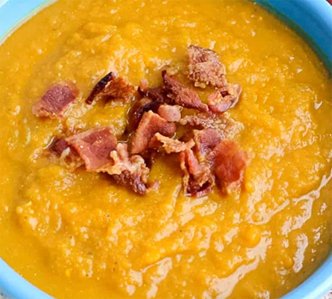 pumpkin and smoked bacon soup served in a bowl topped with chopped bacon