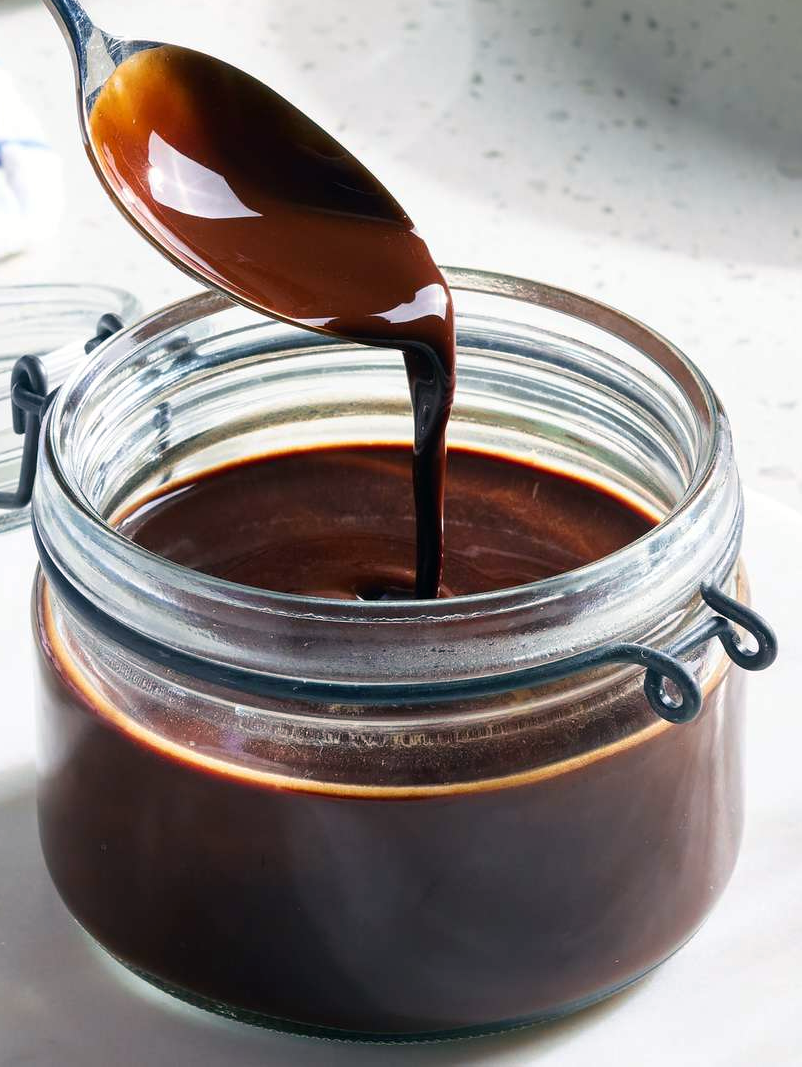 home-made chocolate syrup spooned into a glass jar