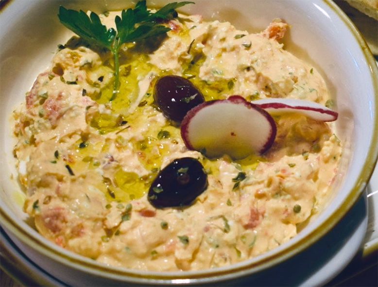 Cypriot chickpea dip topped with olives, radishes and a sprig of flat-leaf parsley