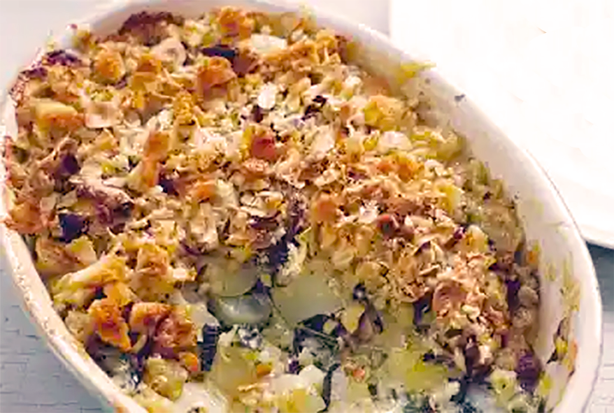 jerusalem artichoke and kale gratin in an oval roasting dish with one portion removed