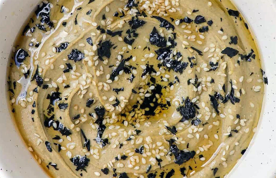kelp and dabberlocks chickpea hummus served in a bowl garnished with sesame seeds