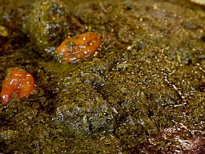 stew of fish, aubergine and cassava leaves with two whole habanero chillies in a large cooking pot