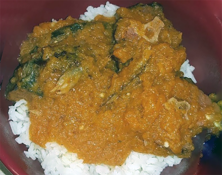 liberian pumpkin stew with meat served over rice in a bowl