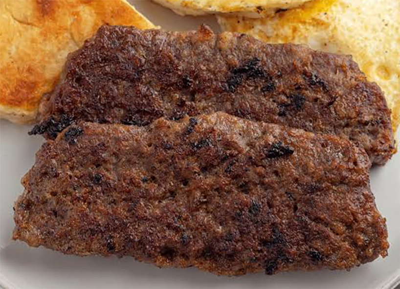 Two fried slices of lorne sausage on a plate with toasted and buttered bread