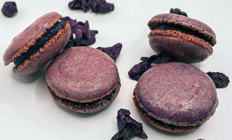 split and sandwiched violet cornmeal macaroons on a work surface