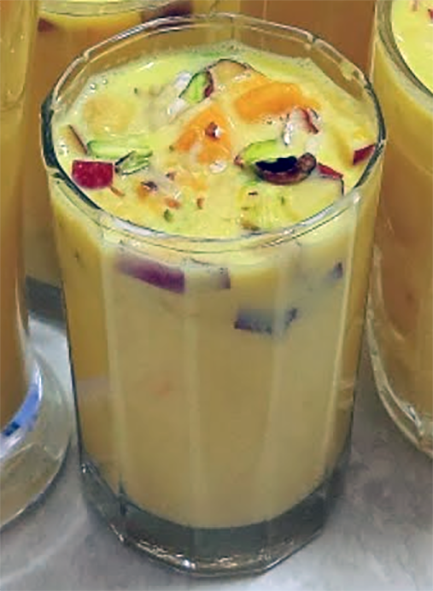 mango sharbat in a glass with garnishes